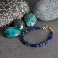 a blue beaded bracelet next to some rocks