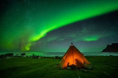 a tent is lit up with the aurora behind it