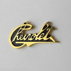 a gold and black brooch with the word kevoel in cursive writing