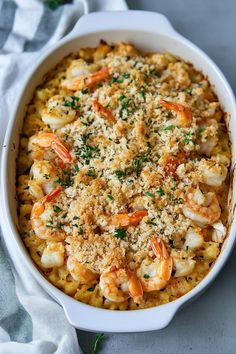 a casserole dish filled with shrimp and pasta, garnished with parmesan cheese