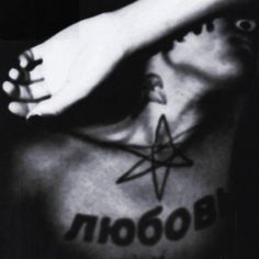 black and white photograph of a person with tattoos on their chest holding his hand up