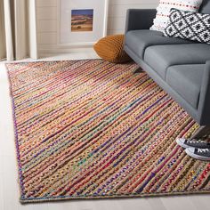 a living room with a gray couch and colorful rugs on the floor in front of a window