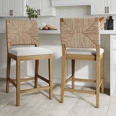 two wooden stools sitting next to each other in front of a white kitchen counter