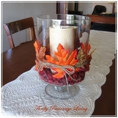 a candle is sitting on a table with autumn leaves