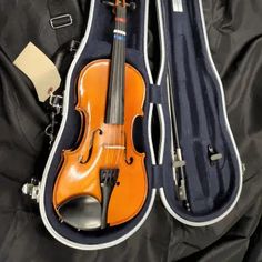 an orange violin in its case on a black cloth