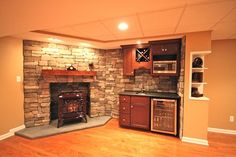 an empty living room with wood floors and stone fireplace