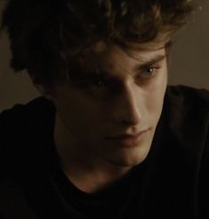 a young man with curly hair looking at the camera