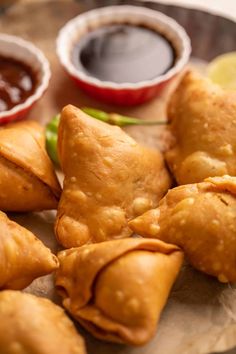 several pastries on a plate with dipping sauces