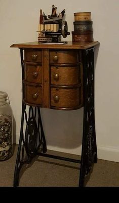 an old sewing machine sitting on top of a wooden table next to a glass jar