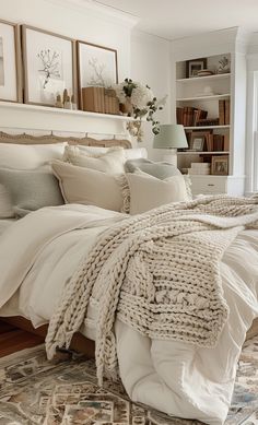 a bed with white linens and pillows in a bedroom next to a book shelf