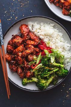 two plates with meat, rice and broccoli on them next to chopsticks