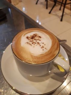 a cappuccino is sitting on a saucer at a restaurant counter top