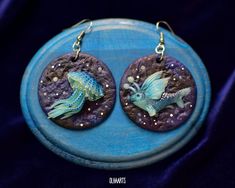 A pair of luminescent earrings with a space jellyfish and a flying fish. It glows in the dark and in UV-light! Also, the pair of earrings goes well with this necklace: https://www.etsy.com/listing/542696040/whale-pendant-polymer-clay-glowing-in?ga_search_query=whale&ref=shop_items_search_1&sca=1 MATERIALS: Polymer clay, metal findings. PARAMETERS: Earrings length (with hook): 6.5 cm (2.6 in) Circle width: 4.5 cm (1.8 in) Circle height: 4.5 cm (1.8 in) ATTENTION! Product color on your mon Whimsical Blue Polymer Clay Earrings, Earrings Space, Sea Jellies, Glowing In The Dark, Custom Figurines, Fantasy Earrings, Ocean Earrings, Flying Fish, Star Jewelry