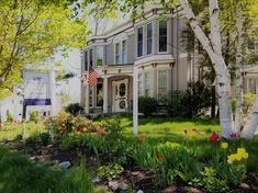 a house with trees and flowers in the front yard