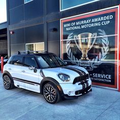 a white car parked in front of a building with a trophy on it's roof