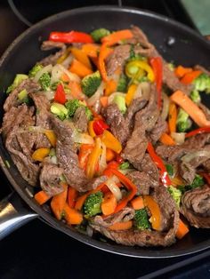 a skillet filled with beef, broccoli and peppers