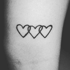 three hearts tattoo on the left inner arm, with one heart drawn in black ink