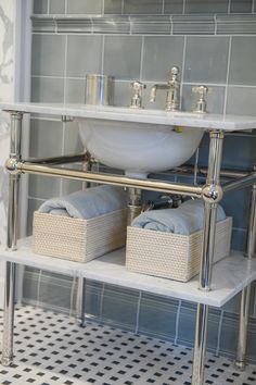 a white sink sitting under a bathroom mirror next to a shelf with baskets on it