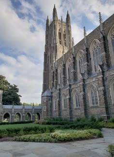 a large cathedral with many windows and arches on the front wall, surrounded by greenery