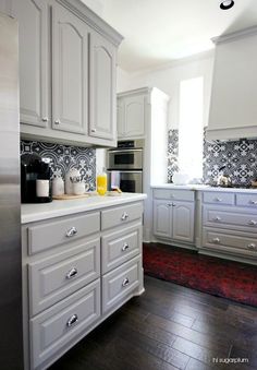 a kitchen with white cabinets and wood floors