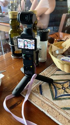 a camera sitting on top of a wooden table next to a bowl of food and bottles