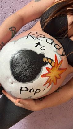 a pregnant woman with her belly painted to look like a rock and the words ready to pop written on it