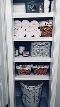 an organized closet with baskets and towels