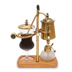 a miniature coffee pot and glass on a wooden stand with an espresso machine next to it