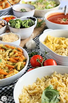 many different types of pasta in bowls on a table with tomatoes and broccoli