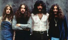 three men standing next to each other in front of a wall with long hair and beards