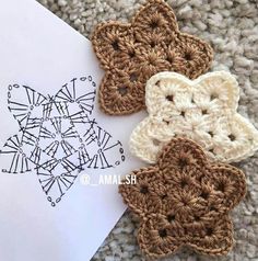 three crocheted flowers sitting on top of a piece of paper