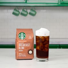 a cup of coffee next to a bag of coffee beans on a counter top in a kitchen