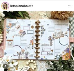 an open planner book sitting on top of a table with flowers and greenery around it