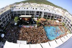 an aerial view of a pool with people swimming in it and onlookers watching