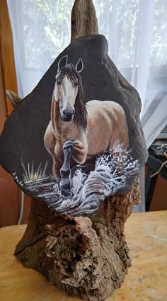 a rock with a horse painted on it sitting on a table next to a window