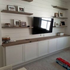 a flat screen tv mounted to the side of a wall in a room with white cabinets