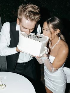 a man and woman are cutting into a cake