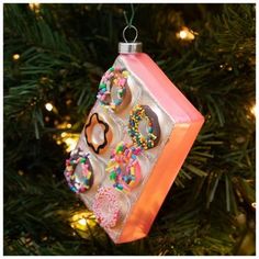 an ornament hanging from a christmas tree decorated with donuts and sprinkles