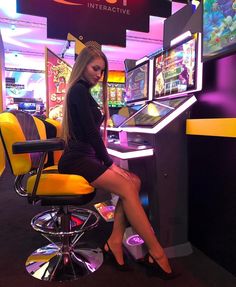 a woman is sitting on a chair in front of a video game machine at the casino