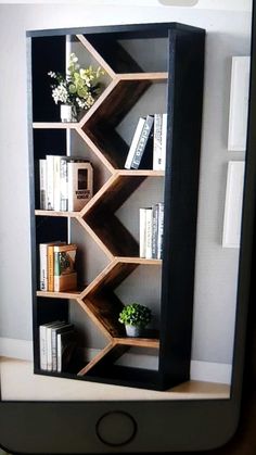 a bookshelf made out of wooden shelves with flowers and books on top, in front of a white wall