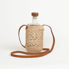 a bottle with a strap around it sitting on top of a white table next to a brown bag