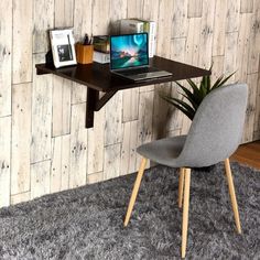 a desk with a laptop on it and a chair in front of the wall next to it