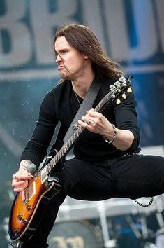 a man with long hair playing an electric guitar