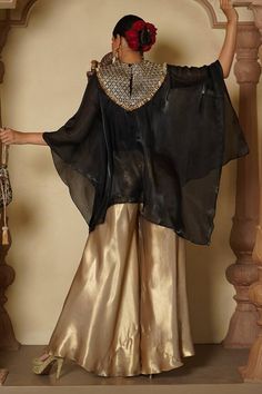 Black batwing sleeves asymmetric cape with fleur jaal embroidery on the yoke using sequin, kiran lace and gold thread highlights. Paired with an inner short kurta and gold flared sharara pant. - Aza Fashions Elegant Traditional Wear With Gota Work For Party, Elegant Traditional Wear For Party With Gota Work, Elegant Party Traditional Wear With Gota Work, Traditional Palazzo Set With Gota Work For Party, Traditional Gota Work Palazzo Set For Party, Traditional Gold Palazzo Set For Party, Elegant Unstitched Blouse Palazzo Set For Eid, Elegant Designer Palazzo Set With Unstitched Blouse, Elegant Chanderi Choli For Party