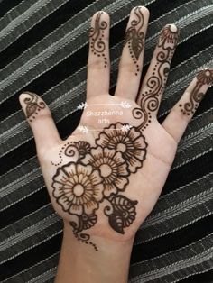 a hand with henna tattoos on it and an intricate flower design in the middle