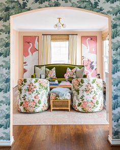 the living room is decorated in pink, green and white with floral wallpaper on the walls