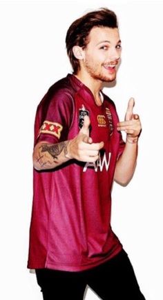 a man with tattoos on his arm giving the thumbs up sign while standing in front of a white background