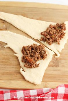 two uncooked pita breads sitting on top of a wooden cutting board