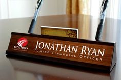 a wooden sign with two pens on it sitting on a table in front of a window