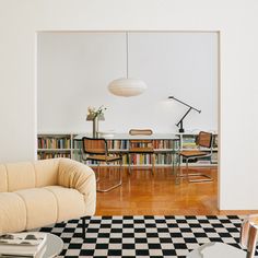 a living room with black and white checkered flooring next to a book shelf